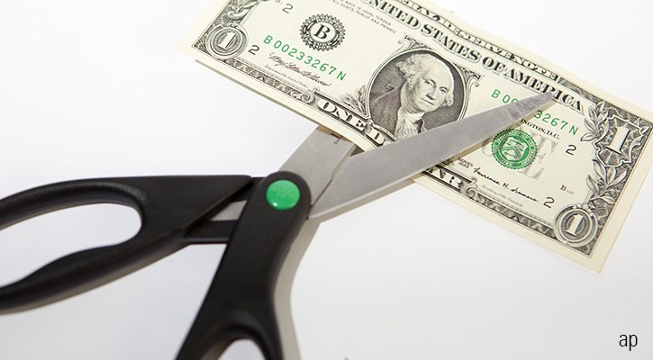 Scissors cutting U.S. dollar bill